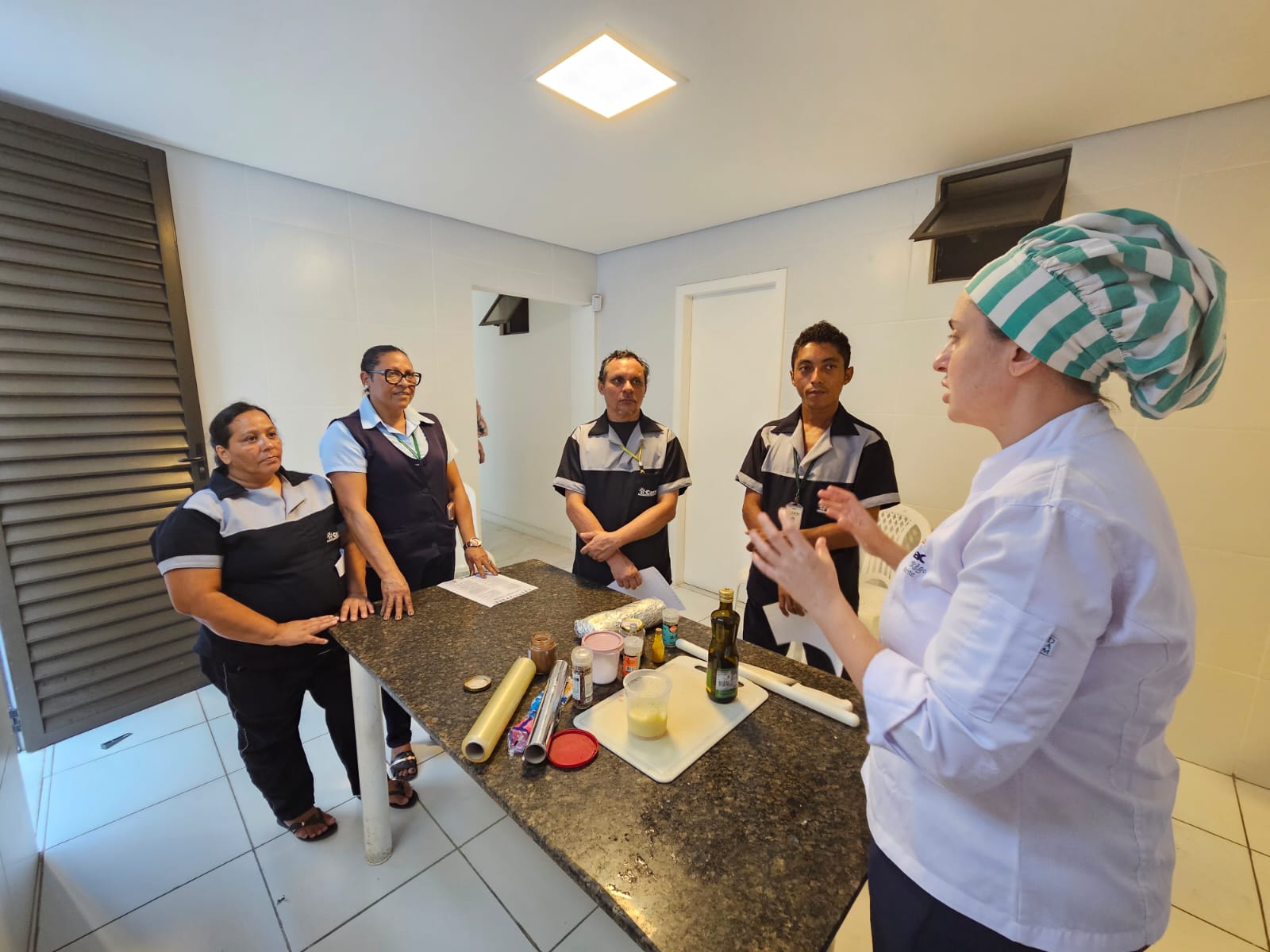 Camila Rêgo, chef, ao orientar colaboradores na oficina